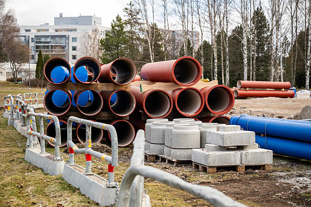 Red construction pipes stacked on wooden pallets at a construction site