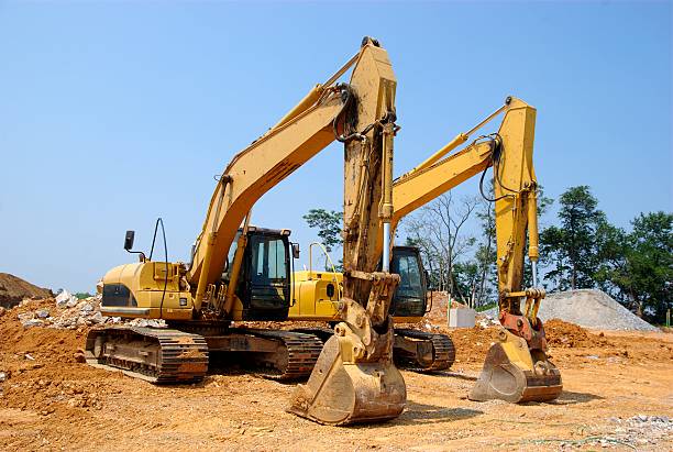 Two excavators rest on a construction site after a long day's work.