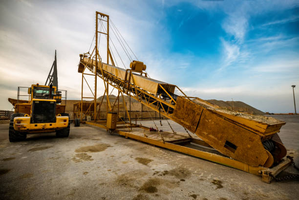 ore belt conveyor and yellow bulldozer excavator on industrial job site